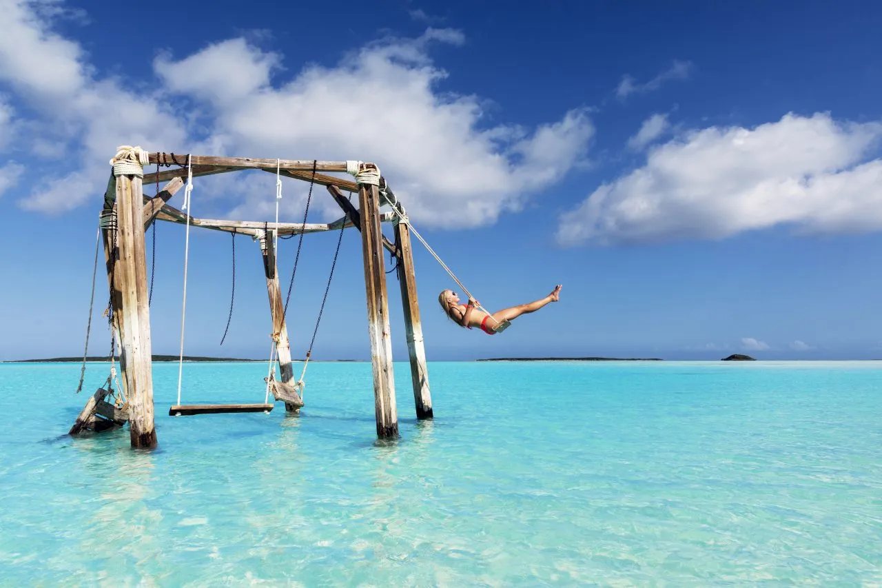 A girl swinging at Cocoplum Beach Exuma, Bahamas