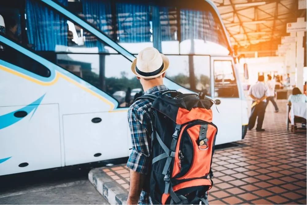 Man with backpack in front of a bus/coach — Shutterstock