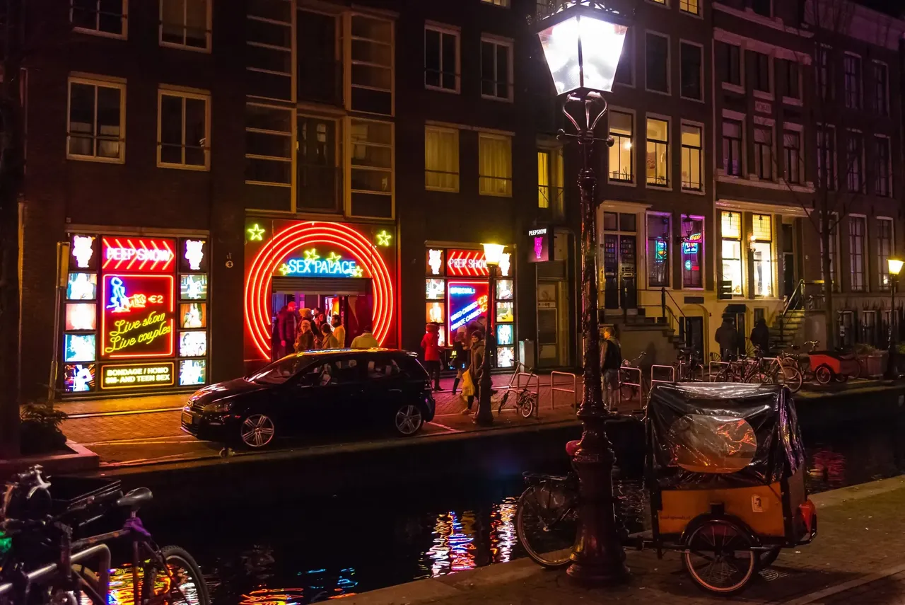 Amsterdami utca, fényesen világító neon feliratokkal: Peep Show, Sex Palace