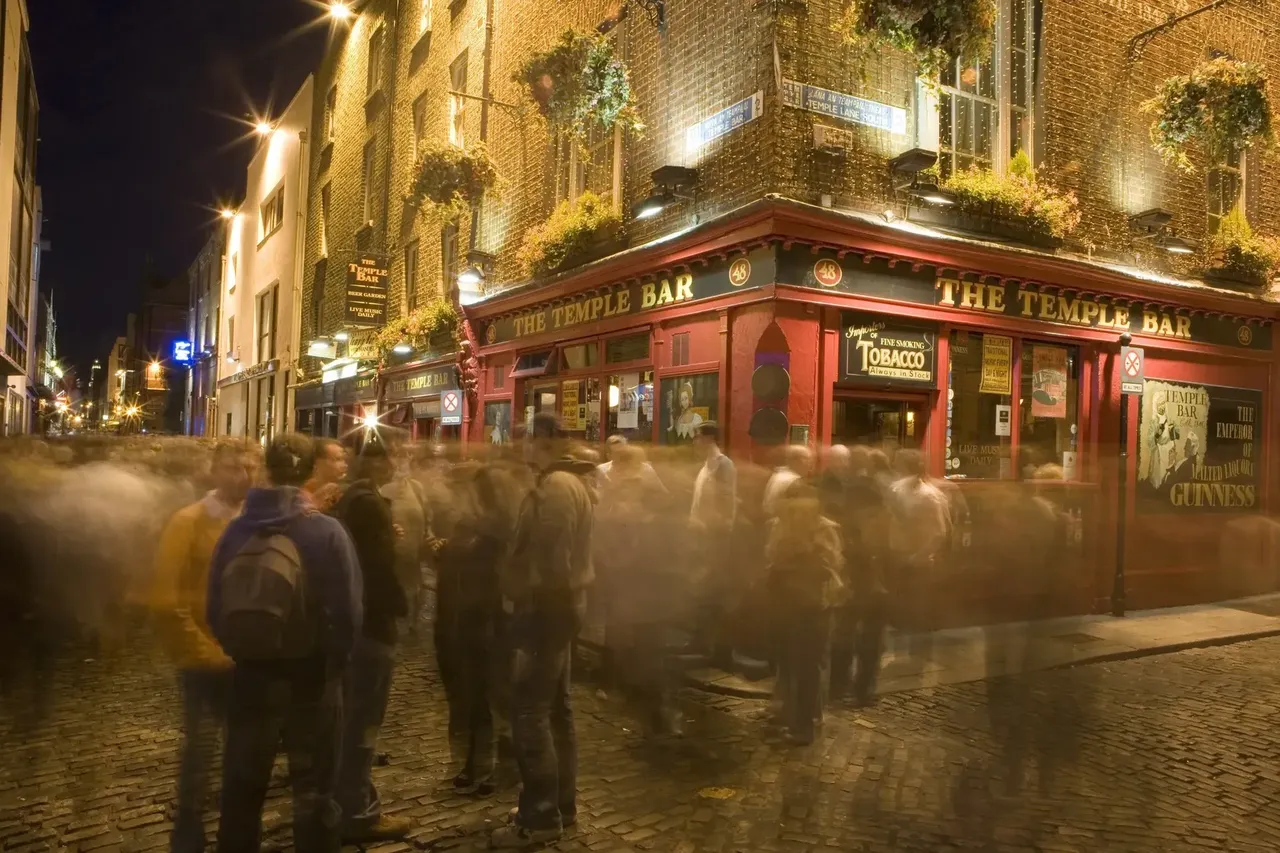 Ludzie przechodzący nocą obok Temple Bar w Dublinie, Irlandia.