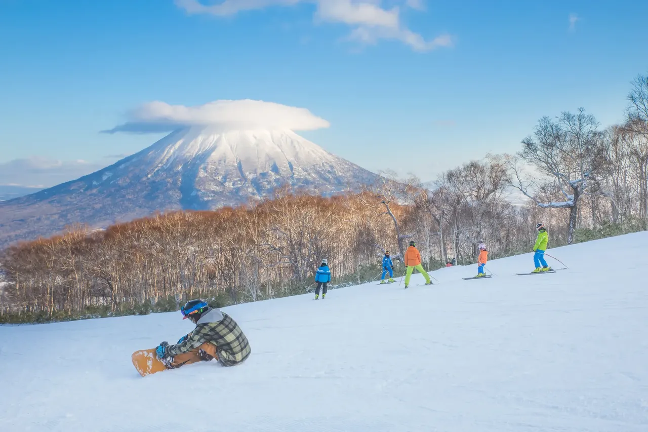 Ludzie na snowboardzie w tle wulkan Yotei