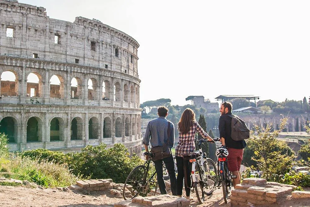 Three friends on a bike standing near the Colosseo in Rome enjoying the view