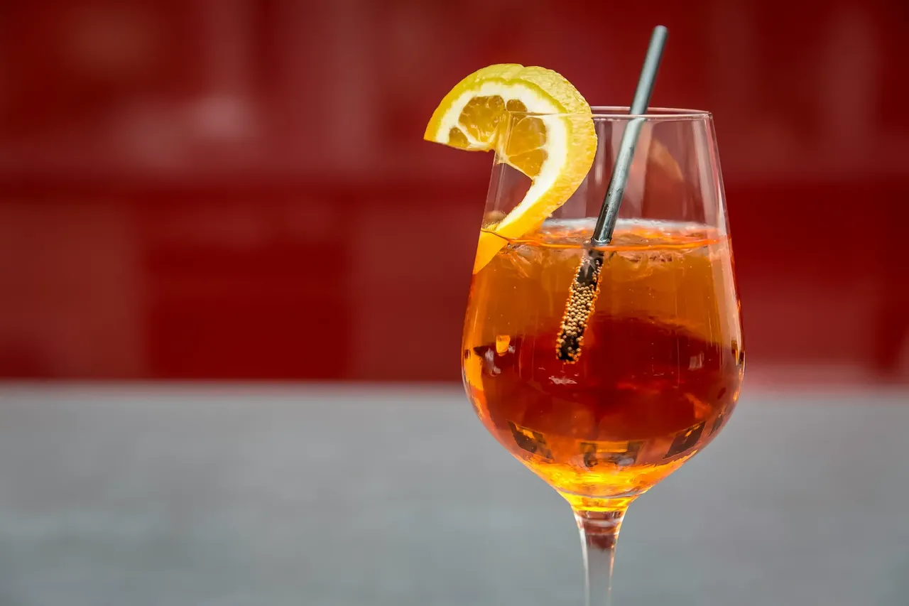 Wibrujący Aperol Spritz serwowany na słonecznym tarasie w Rzymie, z plasterkiem pomarańczy i oszałamiającym tłem.