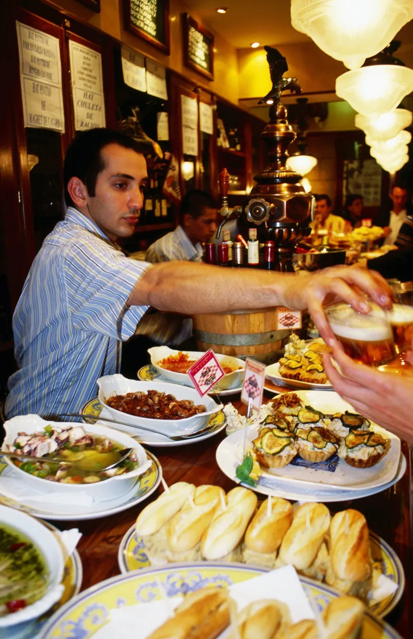 Pinxtos (tapas) on counter of busy Ormazabal Taberna bar, San Sebastian, Spain