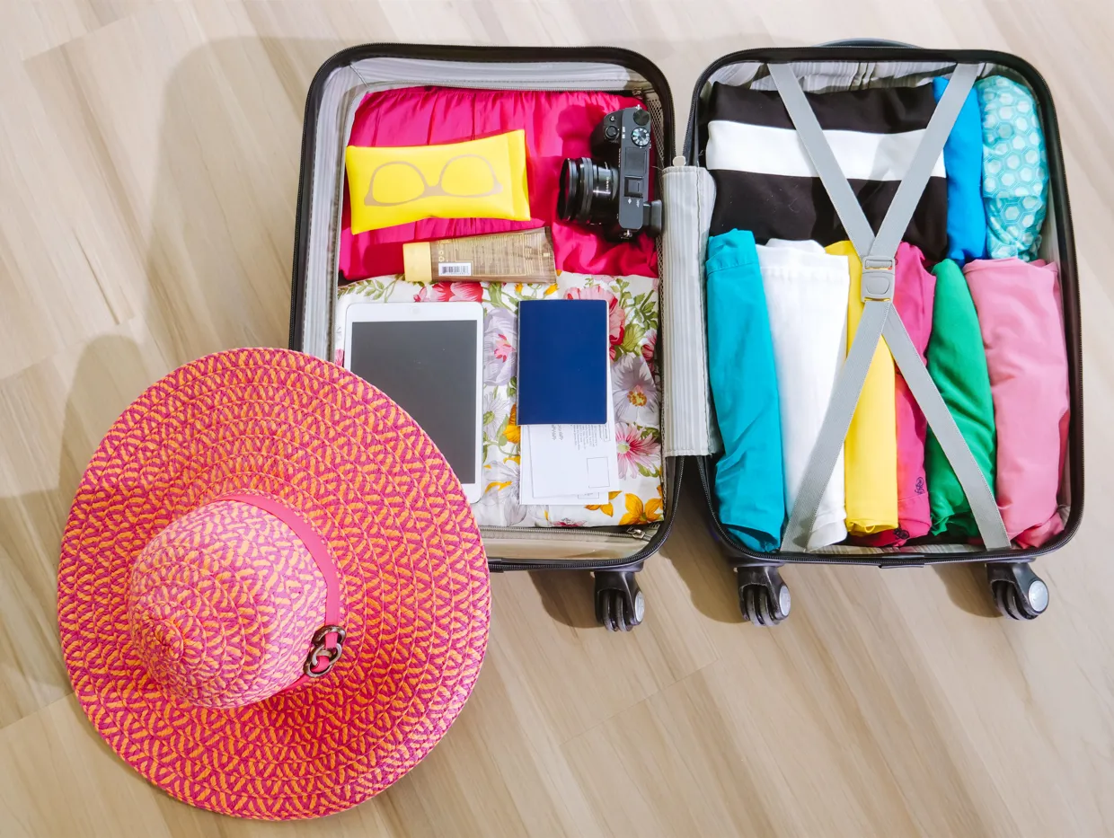 Traveler packing a suitcase with packing cubes and clothes laid out on the floor
