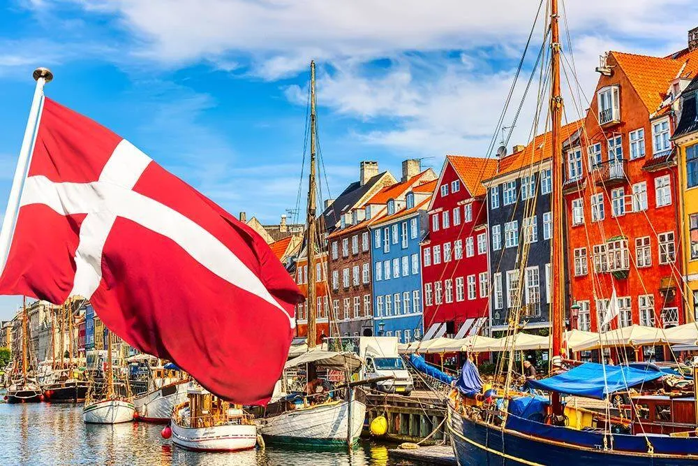 Słynny, stary port Nyhavn w centrum Kopenhagi, Dania, z flagą Danii na pierwszym planie