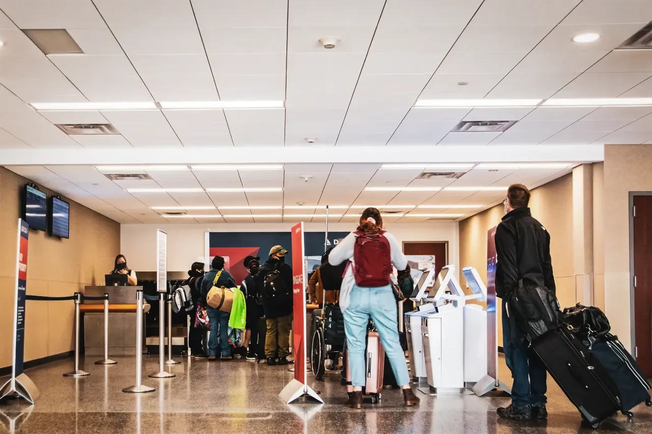 A bustling airport terminal filled with travelers, many carrying luggage, as they navigate through check-in and security lines for holiday travel during Thanksgiving.