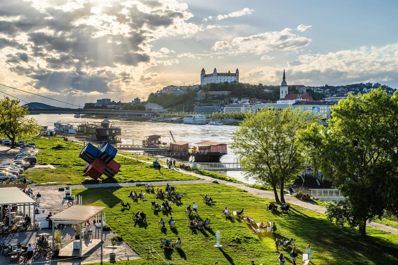 a view of Bratislava Castle from near the Danube river with lots of people