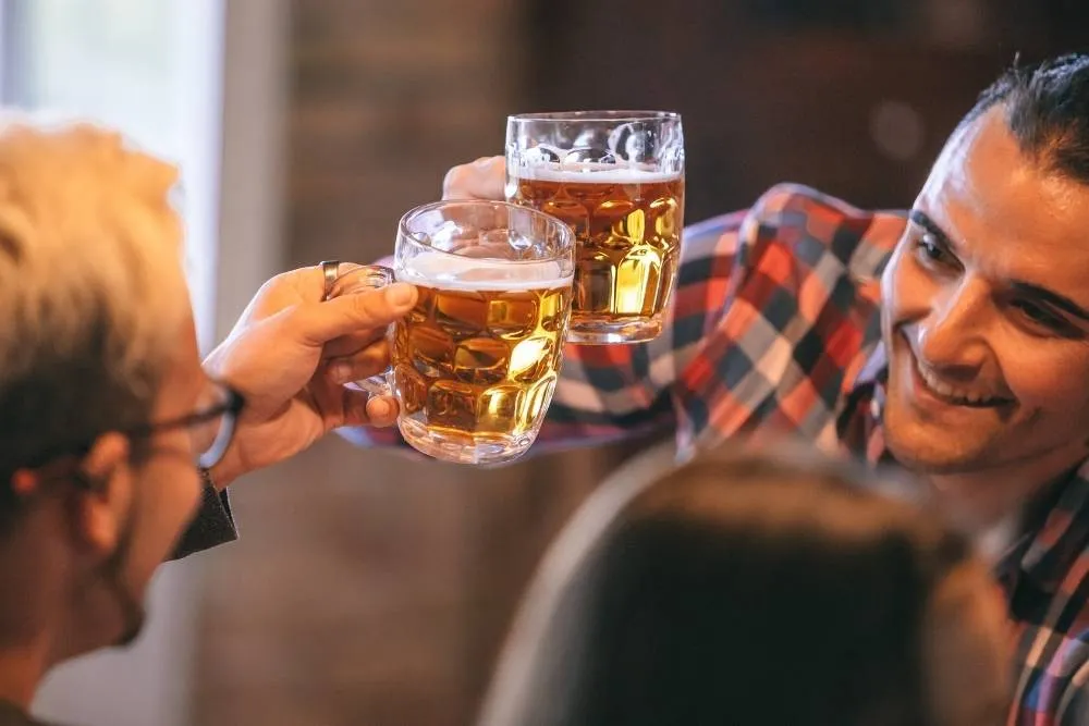 Two friends clinking beers — Shutterstock