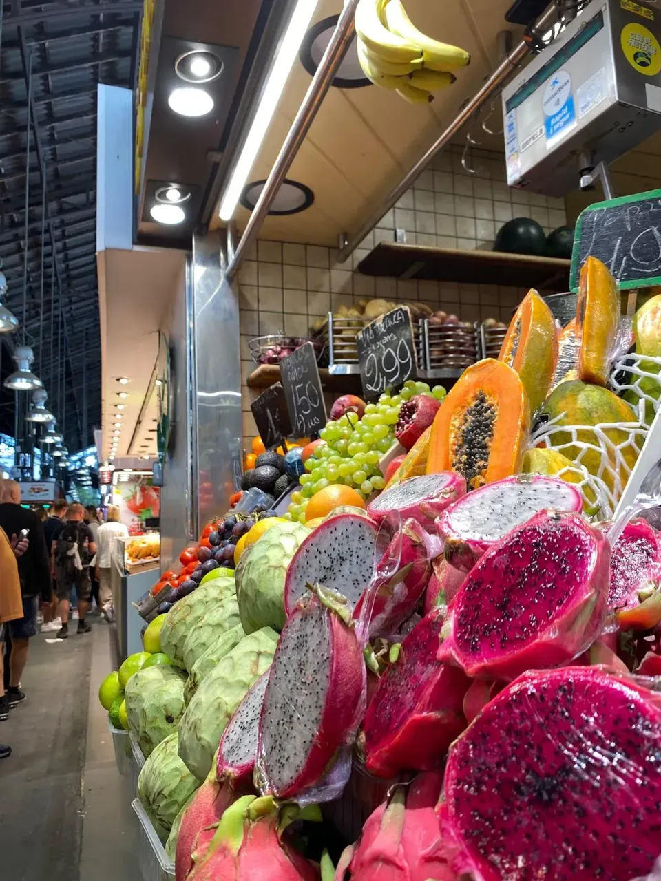 O expunere vibrantă de fructe proaspete la Mercat de la Boqueria, cu varietăți colorate, aranjate în grămezi ordonate.