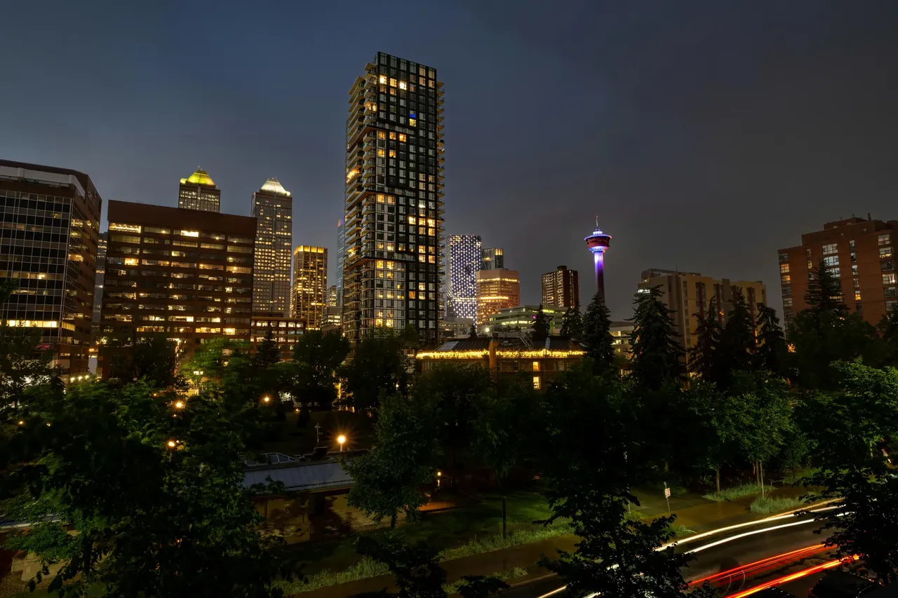 A night view of Inglewood, Calgary, featuring a vibrant skyline with city lights illuminating the streets and buildings under a dark sky.