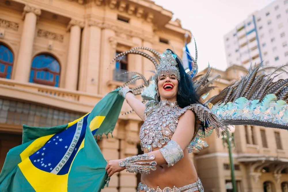 Karneváli ruhás nő integet a brazil zászlóval - Shutterstock
