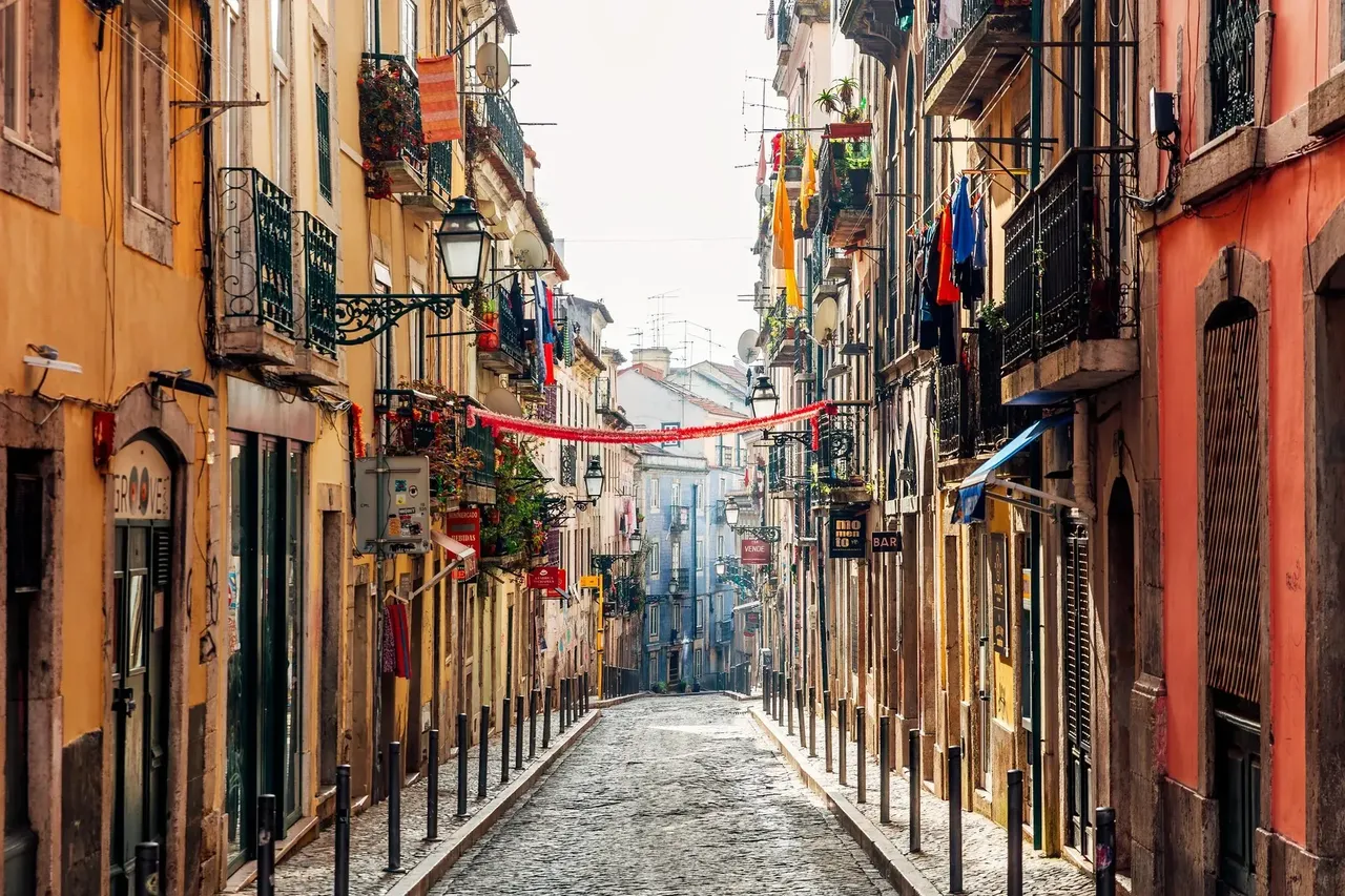 A quiet street in Lisbon’s Bairro Alto district, featuring traditional Portuguese architecture with colorful buildings and narrow cobblestone lanes