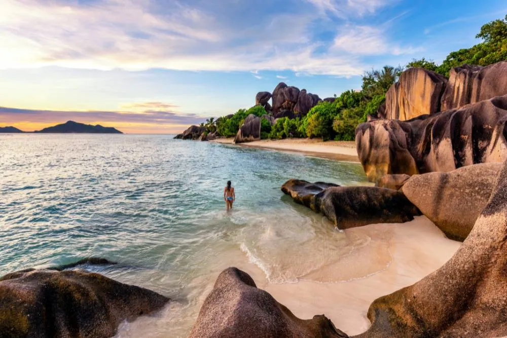 Wide shot of person in the ocean on Anse Source d’Argent — Getty Images