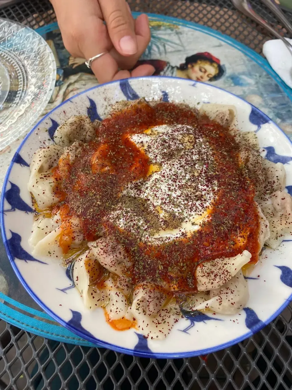 A dish of Turkish manti, small dumplings filled with spiced meat, served with a dollop of yogurt and drizzled with melted butter and red pepper flakes.