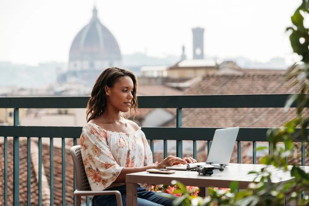 Nő a lapopjával a tetőn ül háttérben Florence látképével — Getty Images