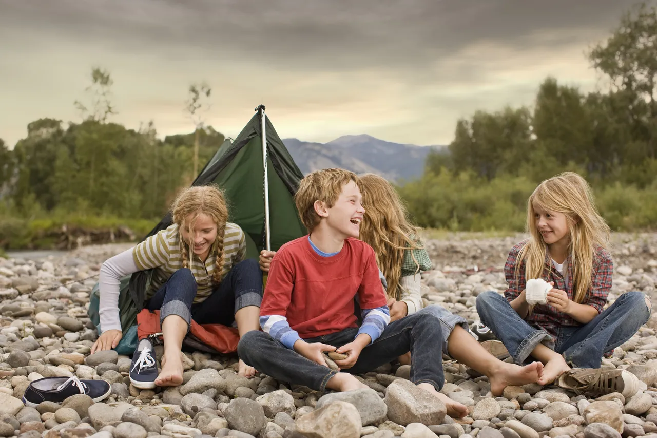 Brother and sisters (8 to 9 years old) playing around a small tent, Bozeman, Montana, United States