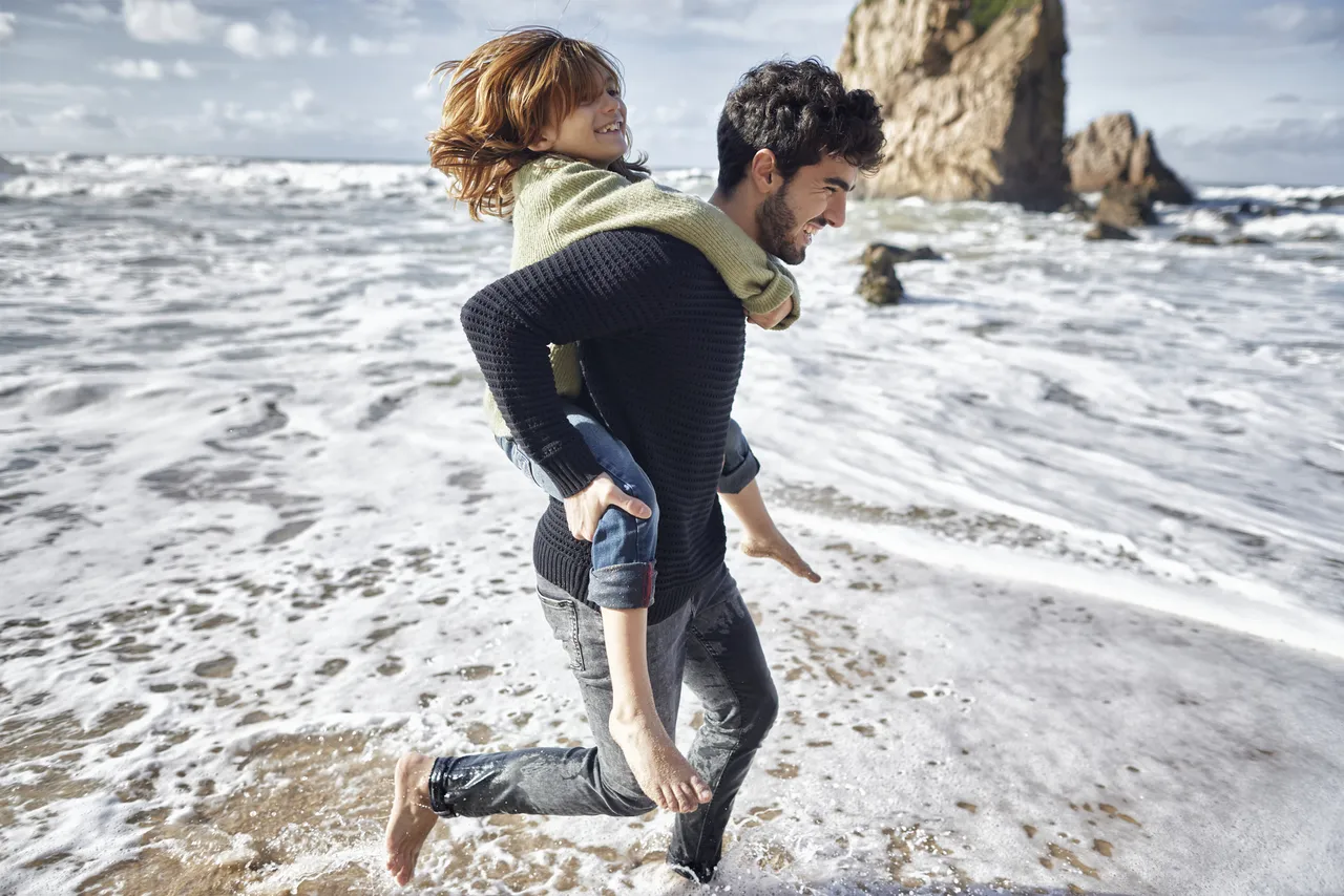 father giving a piggyback ride to his son along the coast