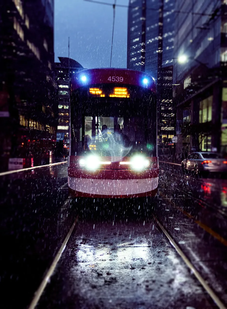 Manchester tram moving through the city at night, with street lights casting a warm glow