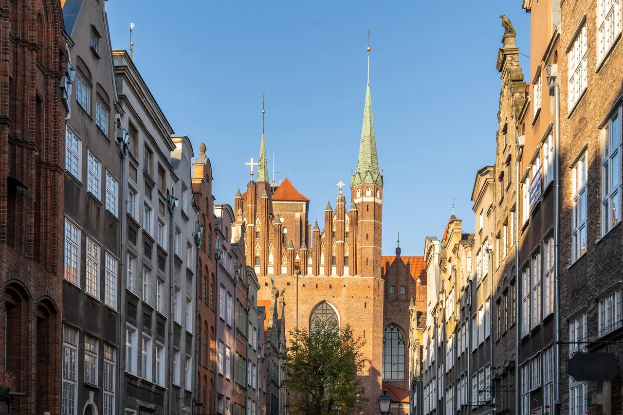 Wysoka iglica Kościoła Mariackiego dominuje nad panoramą widzianą z wąskich, zabytkowych ulic Gdańska.