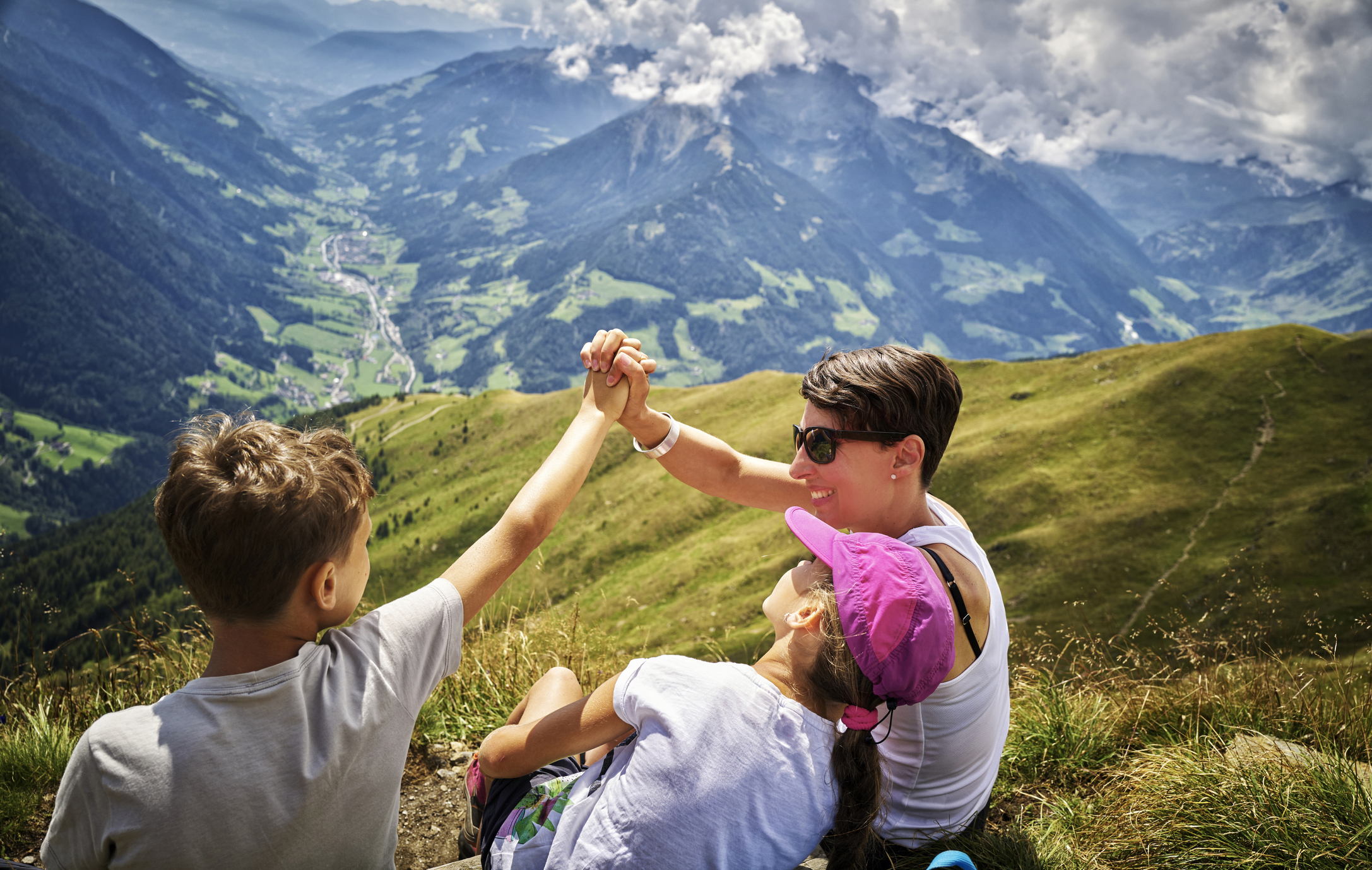 Mother with a daughter and a son having a break on top of a mountain in Alps
